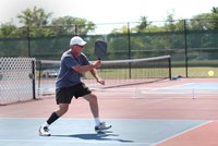 A senior man hits a shot while competing in a pickleball tournament